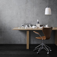 Modern workspace featuring a gray wall, wooden desk, brown chair, and black flooring with subtle patterns.