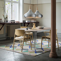 Stylish dining set featuring wood tones and a colorful geometric patterned rug with blues, greens, and pastels.