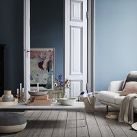 Modern living room with muted blue walls, earthy tones in decor, and minimalist patterns on textiles and art.