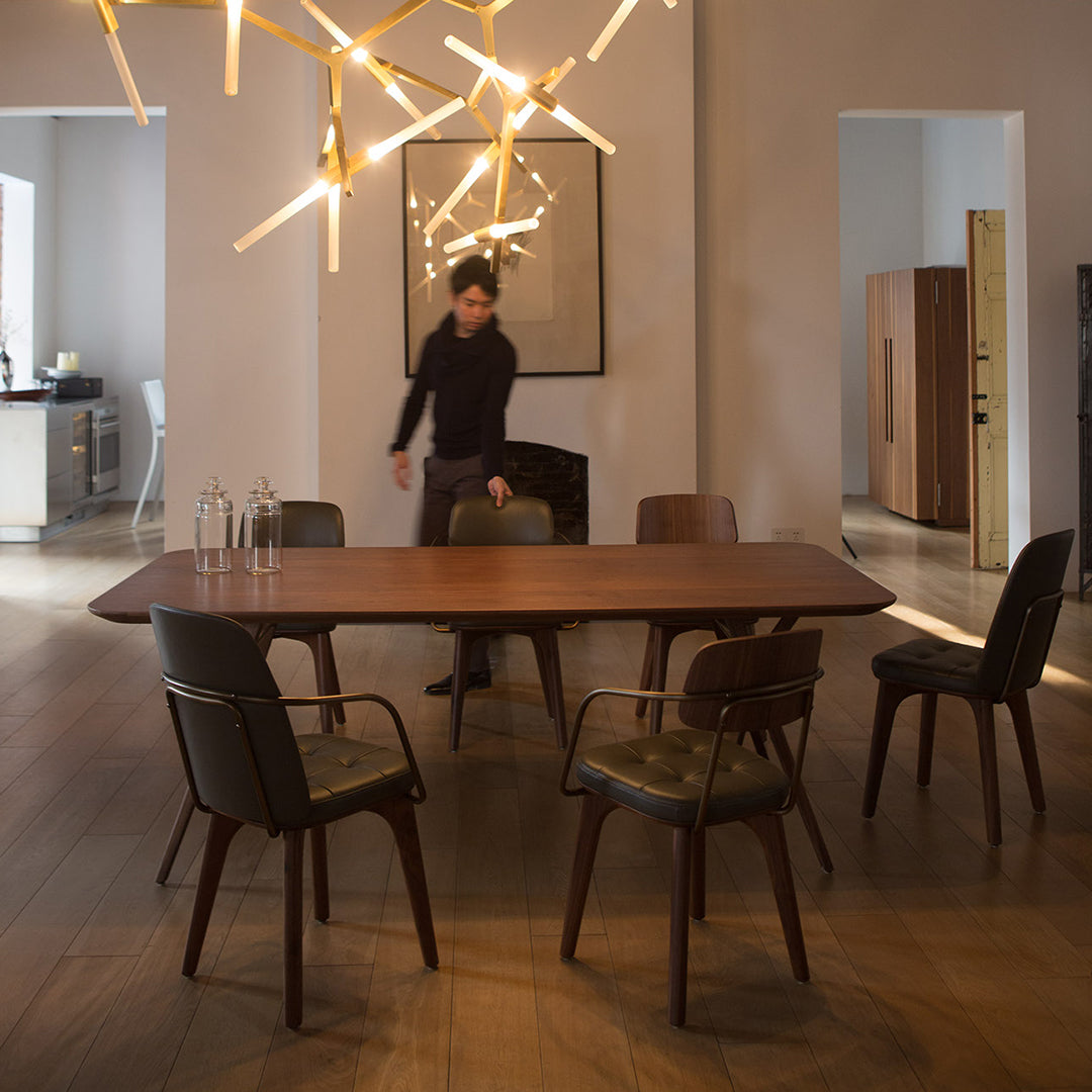 Stylish wooden dining table with dark patterned chairs, set against a modern, neutral-toned interior.