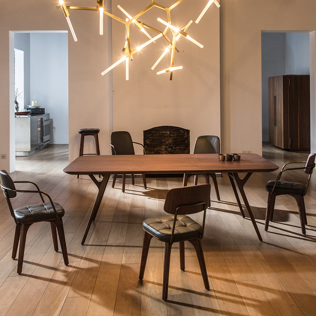 Modern wooden dining table with sleek black chairs, warm wood tones, and a minimalist design. Bright lighting enhances elegance.