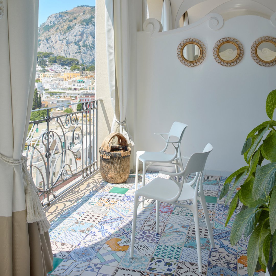 Colorful patterned tiles in a mosaic design, featuring shades of blue, purple, yellow, and white, set in a bright balcony.