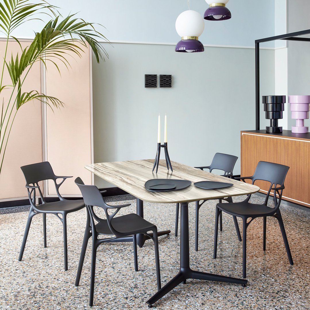 Stylish black chairs around a light wood table, complemented by pastel walls and sleek decor accents.