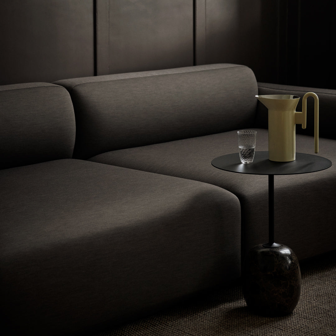 Modern dark gray sofa with smooth fabric. Stylish minimalist side table in black and beige accents.