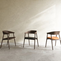 Set of three modern wooden chairs featuring dark walnut tones with black and orange cushions.