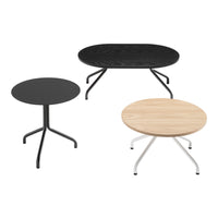 Three modern coffee tables: one round black, one oval black with textured finish, and one light wood finish with white legs.