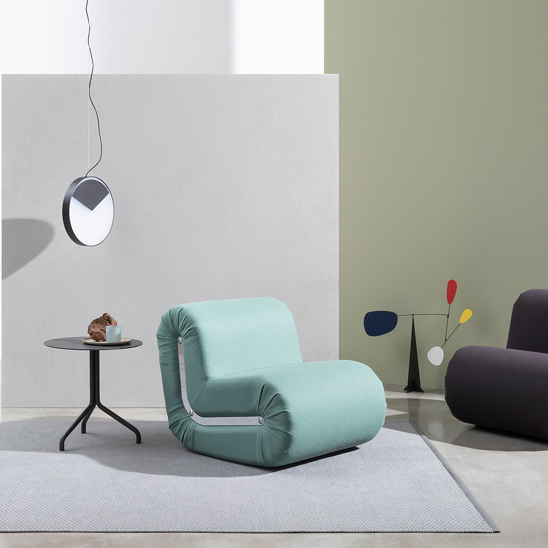 Mint green chair with ruched design, set against neutral walls and a light gray rug in a modern interior.