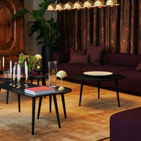 Elegant living room featuring deep purple accents, a black coffee table, and warm golden lighting against a beige carpet.