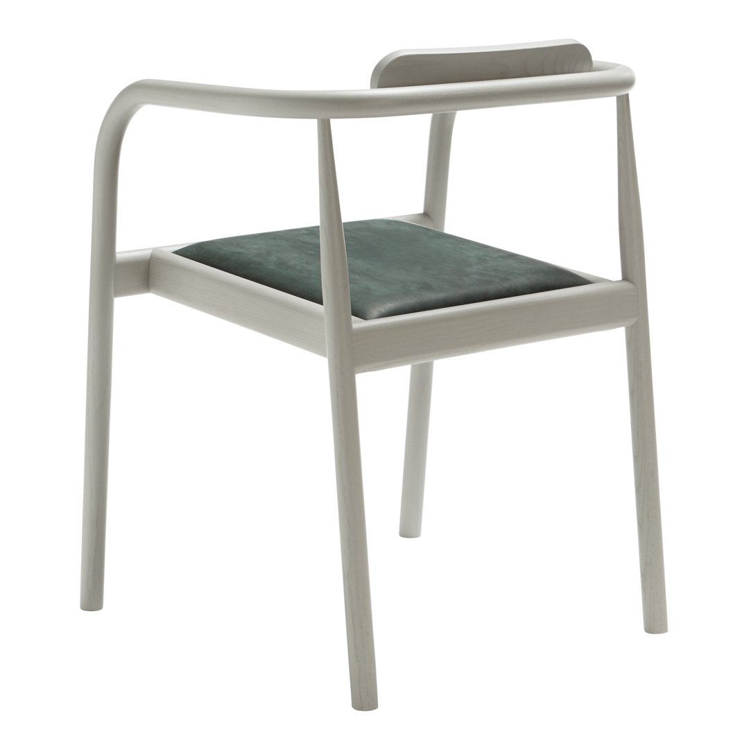 Light gray chair with a simple design and dark green velvet cushion, creating a modern, stylish look.