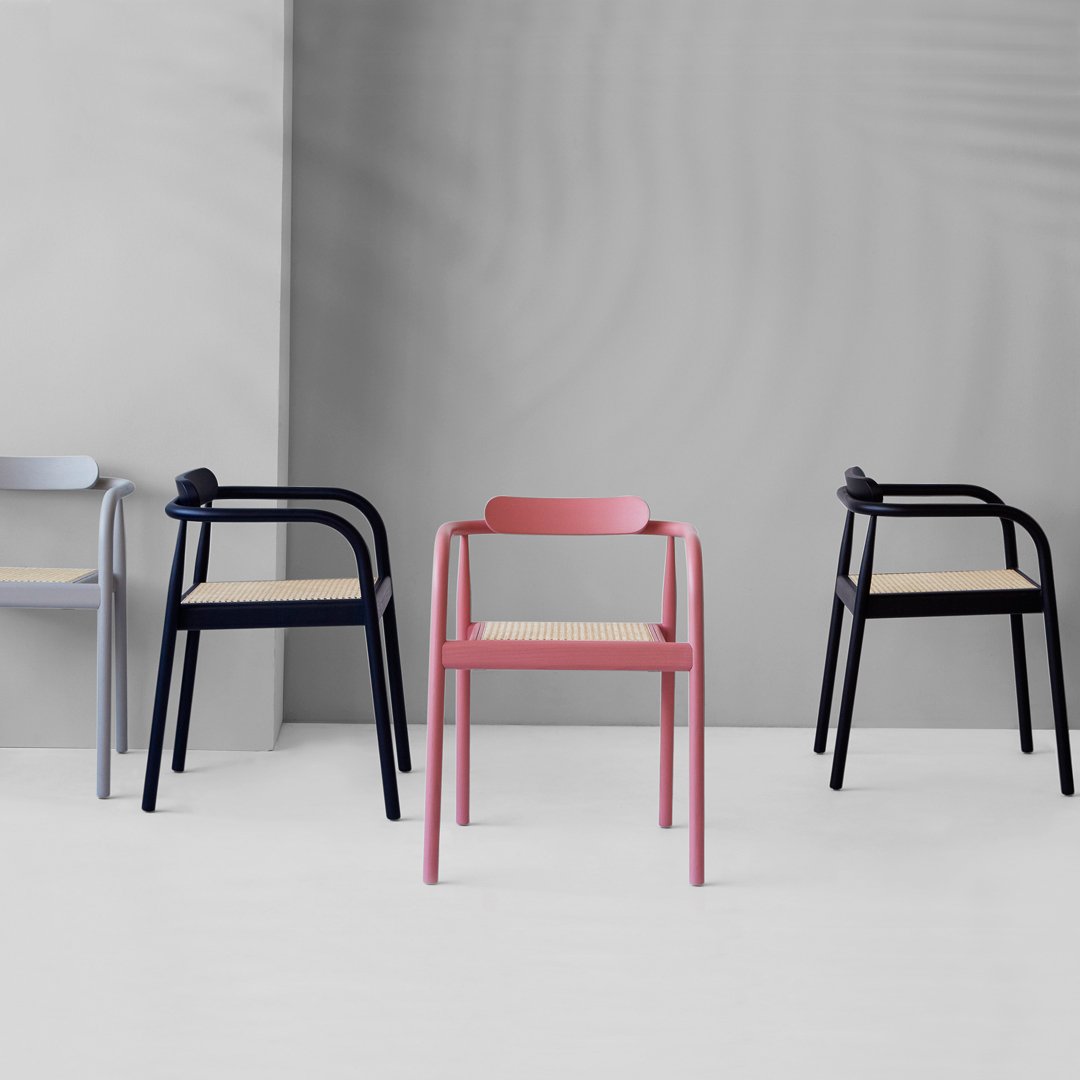 Colorful modern chairs in pink, grey, navy, and black with minimalistic designs and natural wood seats.