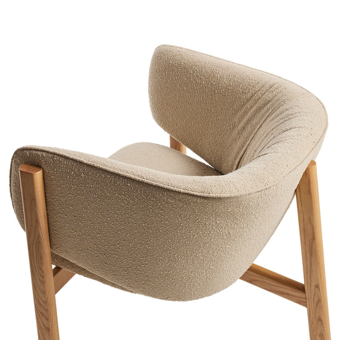 Beige plush chair with a curved back and natural wood legs, showcasing a soft texture and minimalist design.