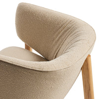 Beige textured chair with curved backrest and natural wooden legs, showcasing soft, cozy fabric and minimalistic design.
