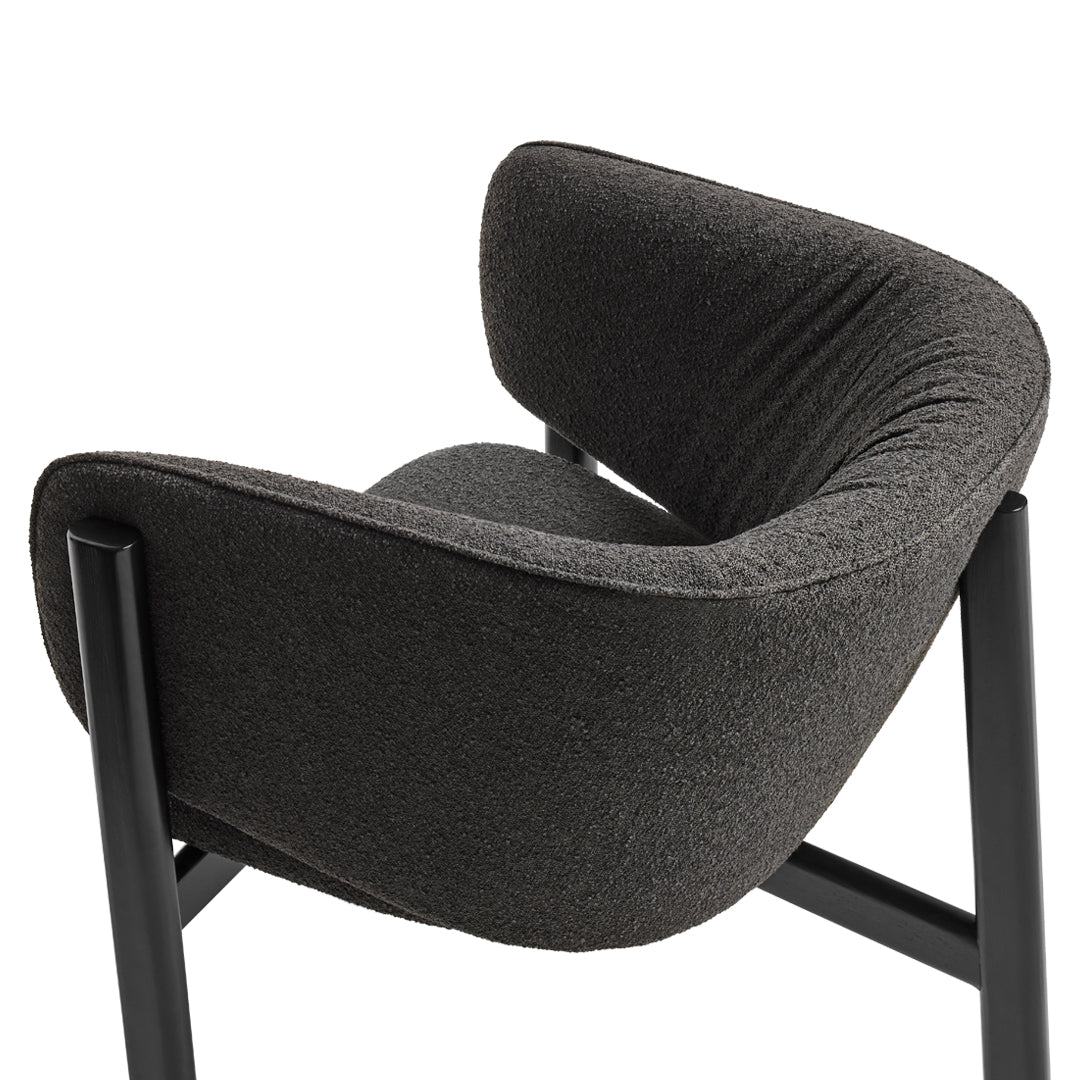 Modern black upholstered chair with contoured backrest and textured fabric, featuring sleek metal legs.