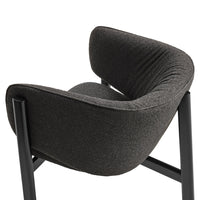 Modern black upholstered chair with contoured backrest and textured fabric, featuring sleek metal legs.