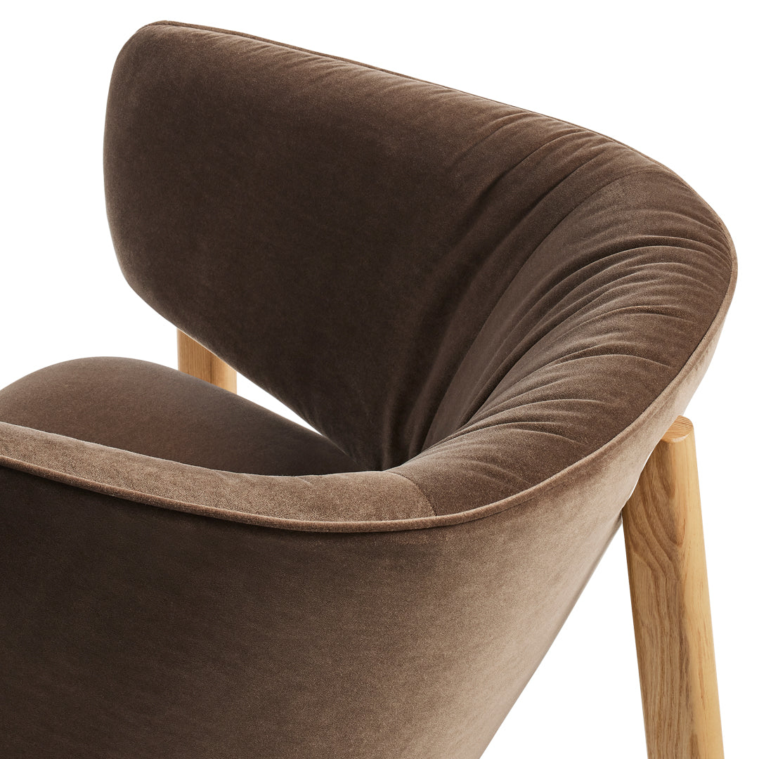 Soft brown velvet chair with a curved backrest and light wooden legs, perfect for adding warmth to any space.
