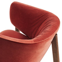 Soft velvet armchair in warm terracotta with smooth curves and a subtle sheen, complemented by wooden legs.