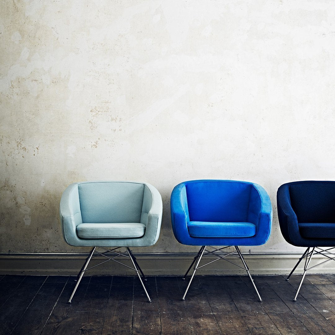 Three modern chairs in soft blue, vibrant cobalt, and deep navy against a textured wall, highlighting minimalist design.