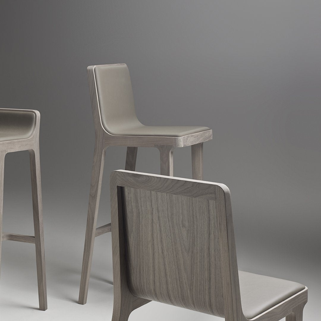 Gray wooden bar stools with sleek lines and minimalist design, featuring a smooth finish and subtle grain patterns.