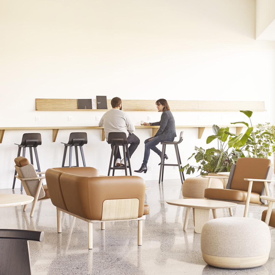 "Modern lounge with neutral tones, brown leather accents, and soft textures, featuring stylish seating and greenery."
