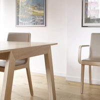 Light oak dining table with smooth beige chairs, minimalist design, and soft natural tones, perfect for modern interiors.