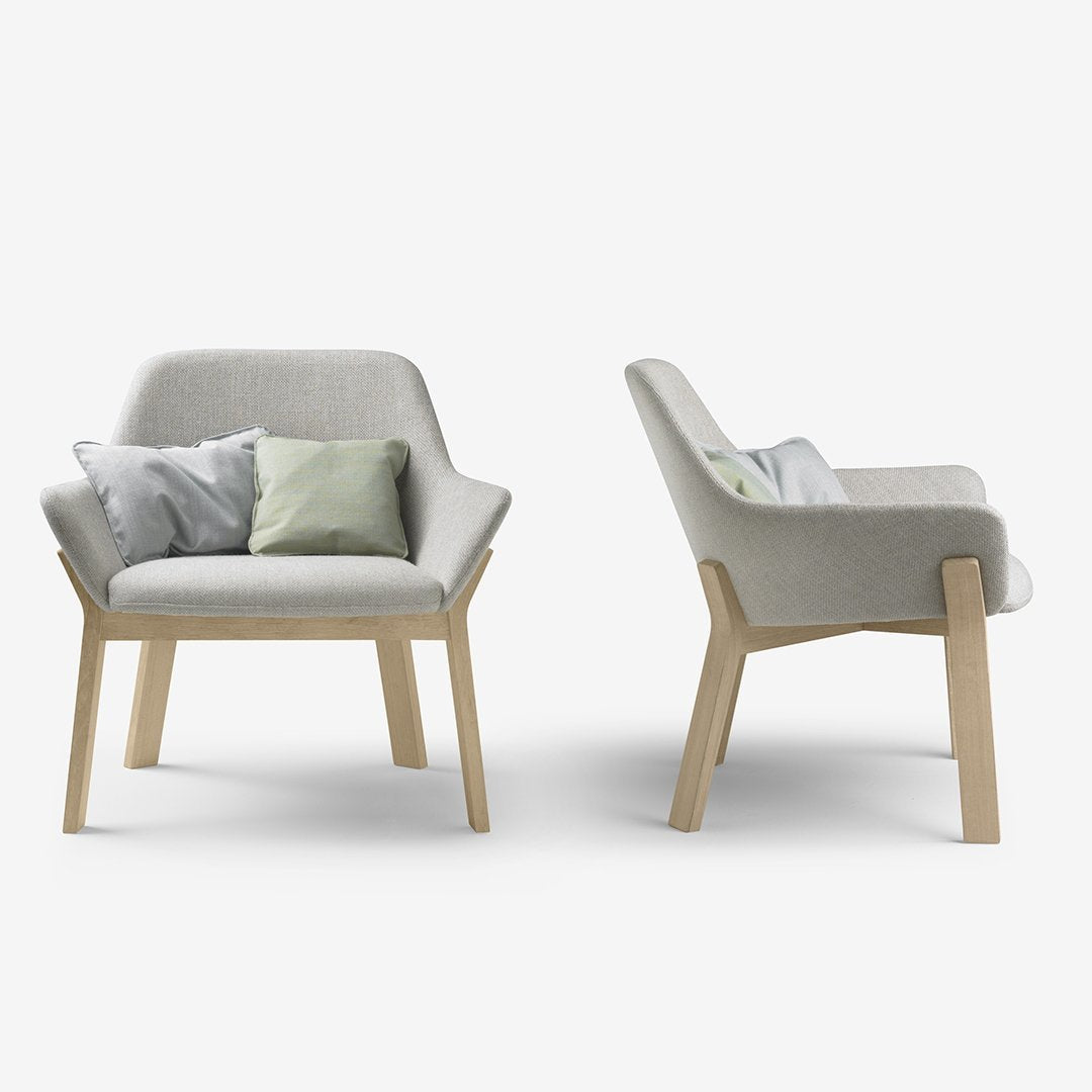 Gray fabric armchair with light wood legs, featuring subtle pastel throw pillows in green and gray.
