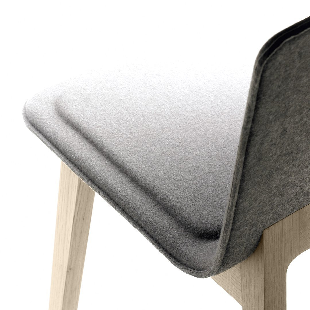Gray textured fabric chair back with light wood legs, featuring a smooth, minimalist design.