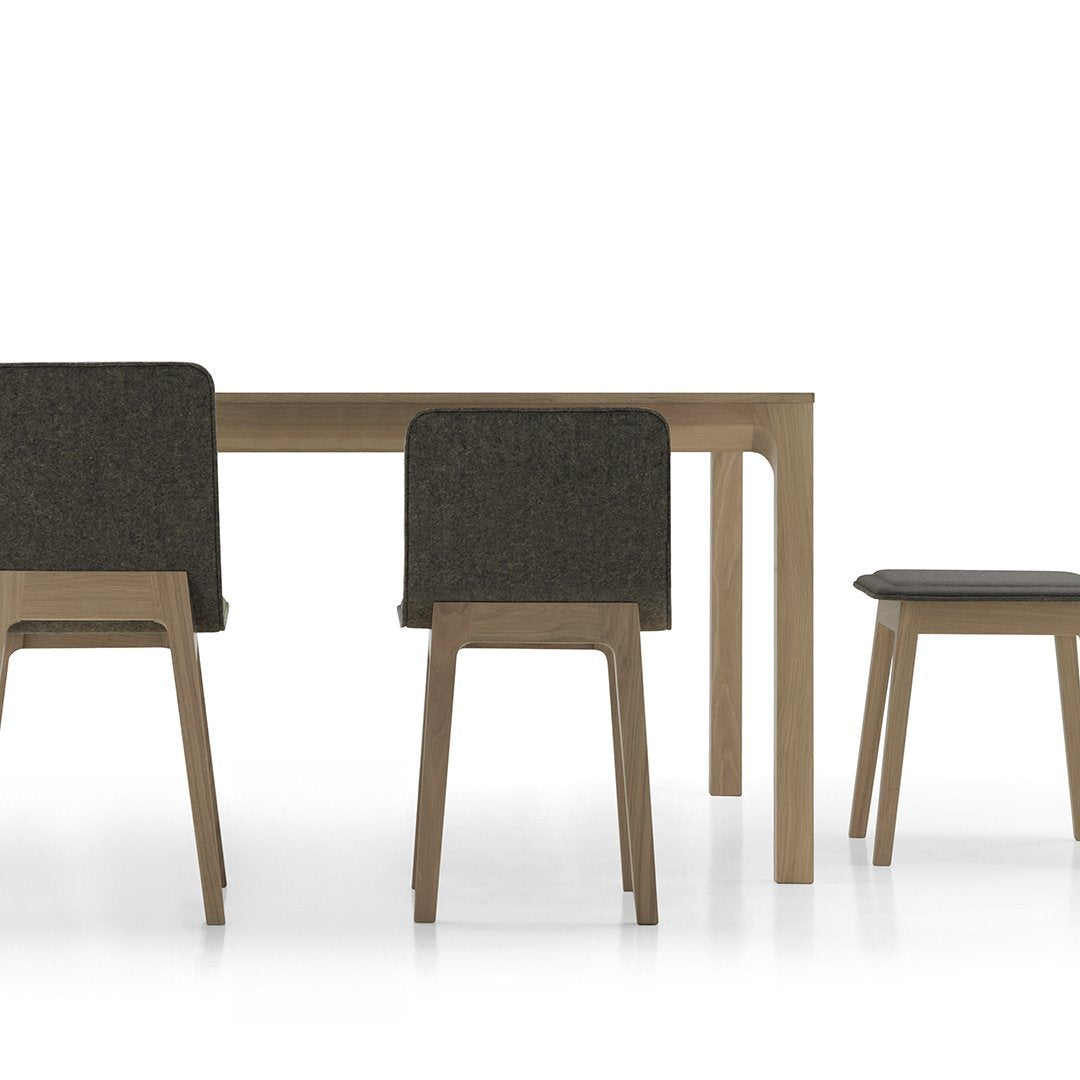 Neutral wood dining table with dark gray upholstered chairs featuring clean lines and minimalistic design.