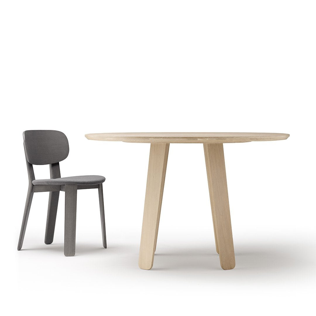 Natural wood round table paired with a sleek grey chair, highlighting minimalist design and neutral tones.
