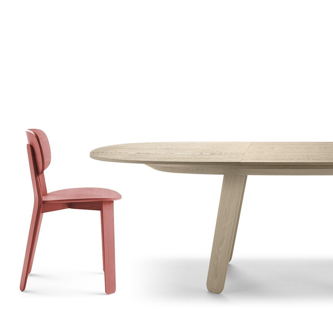 Light oak dining table paired with a soft pink chair, featuring smooth surfaces and modern, minimalistic design.