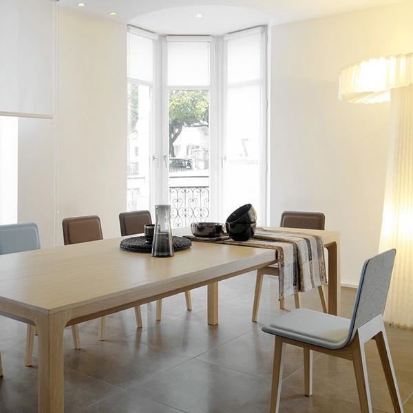 Modern dining room featuring a light wood table, grey and brown chairs, and a neutral color palette.