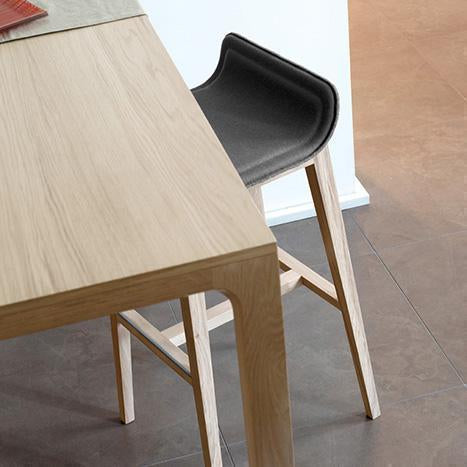 Modern wooden table with light oak finish and sleek black upholstered stool. Clean lines and natural textures.