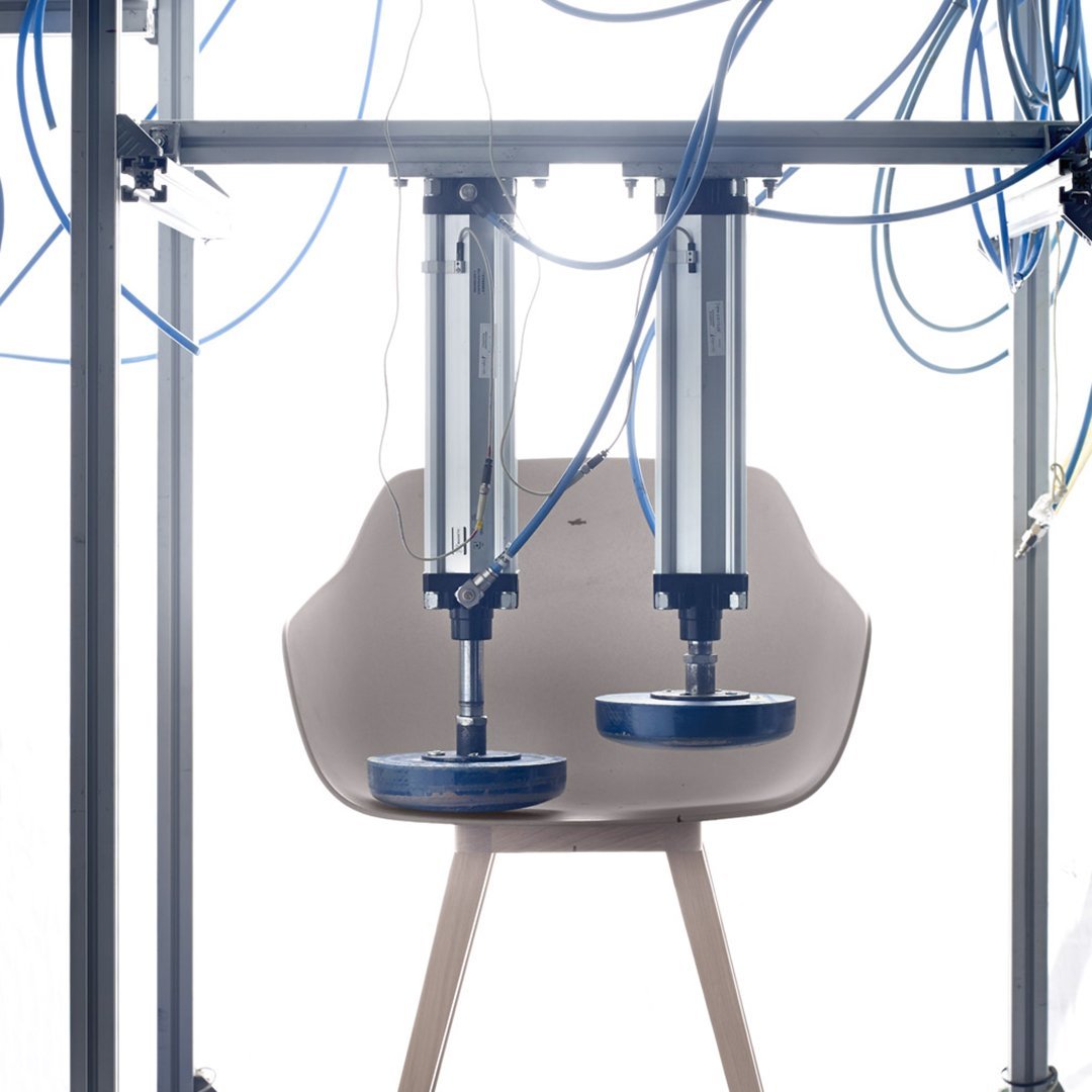 Minimalist beige chair with light wood legs, surrounded by blue cables against a bright background.