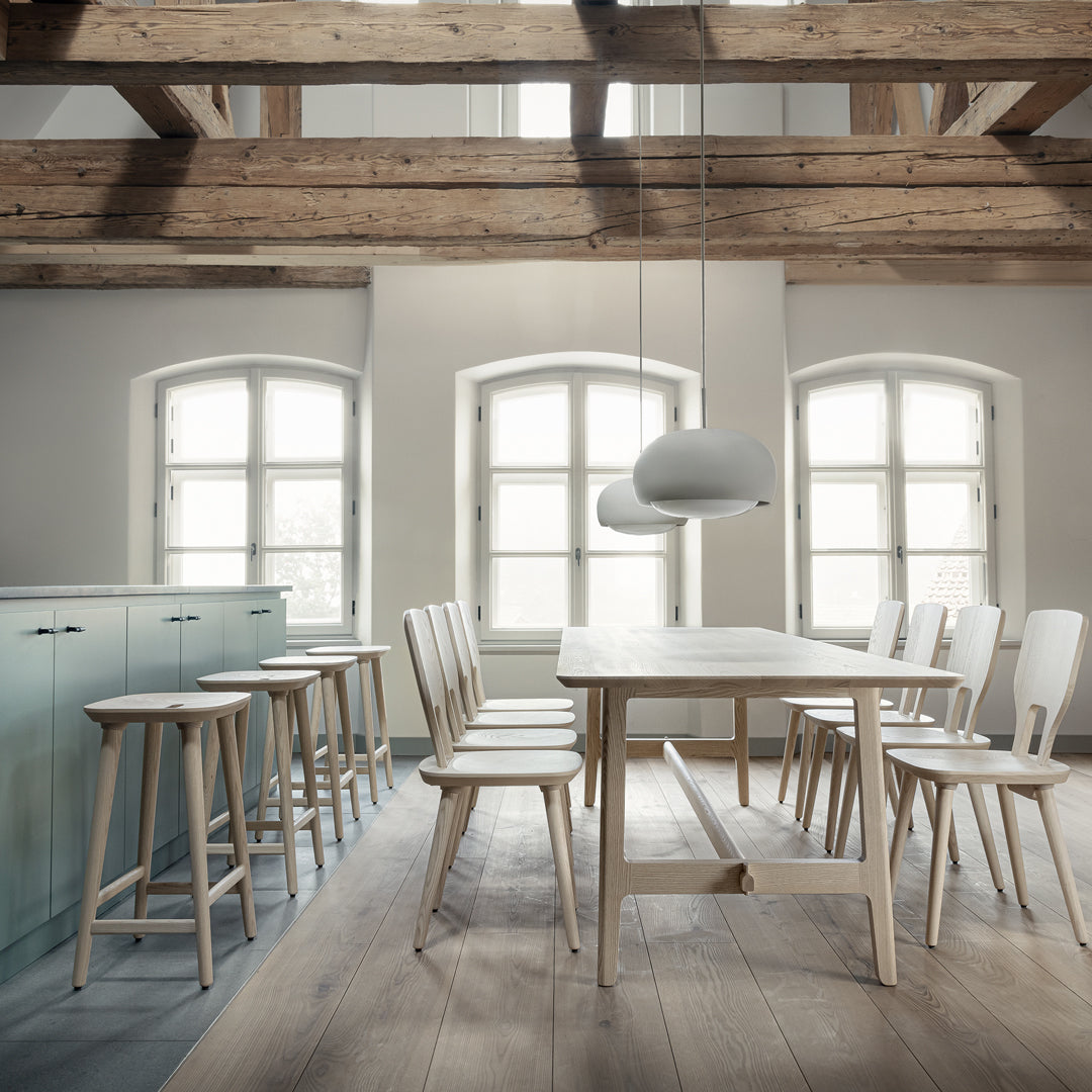 Light wood furniture with a minimalist design, featuring soft gray cabinetry and warm wooden beams in a bright, airy space.