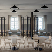 Minimalist wooden chairs with natural hues, black accents, and neutral-toned patterned walls in a modern setting.