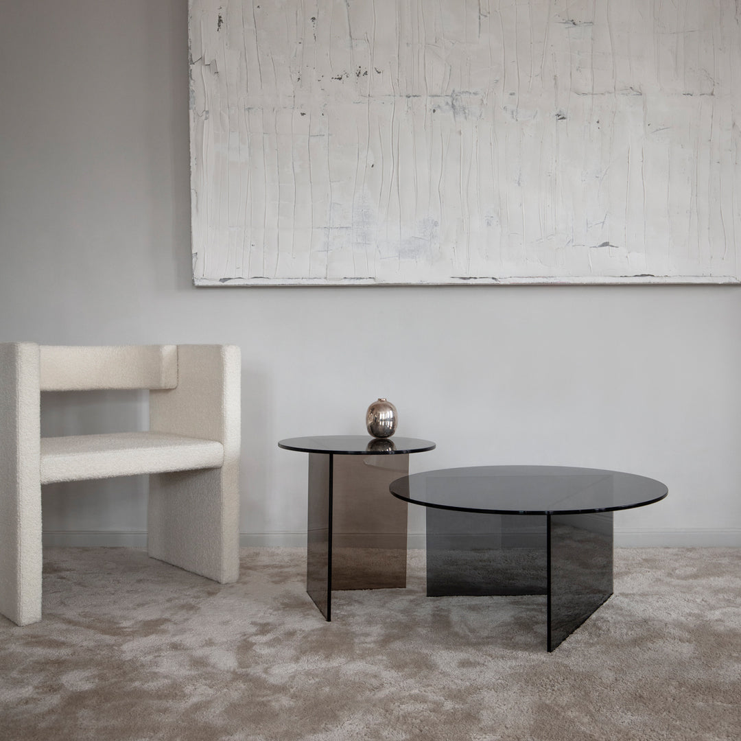 "Elegant black glass coffee tables with sleek geometric shapes, paired with a minimalist white chair on a neutral carpet."
