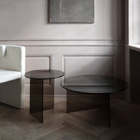Black glass coffee tables with sleek, minimalist designs, set against a soft, neutral-toned interior.