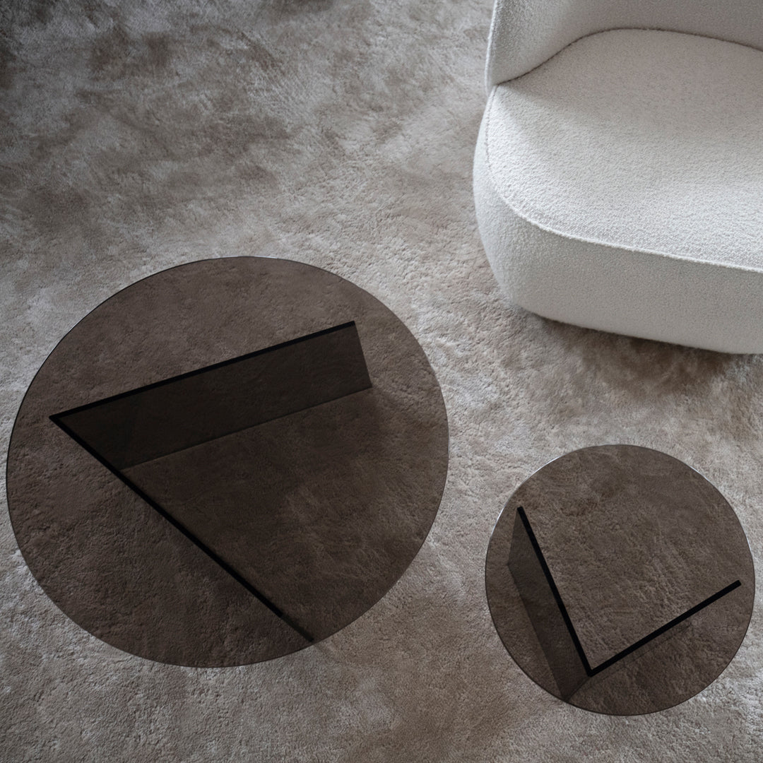 Modern glass coffee tables in dark brown hues with geometric patterns, set on a soft beige carpet.