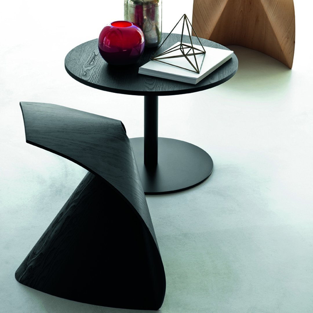 Black geometric coffee table with a sleek round top and bold angular side table; deep red and silver accessories enhance the look.
