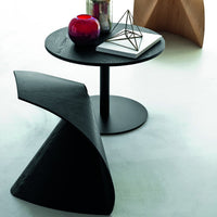 Black geometric coffee table with a sleek round top and bold angular side table; deep red and silver accessories enhance the look.