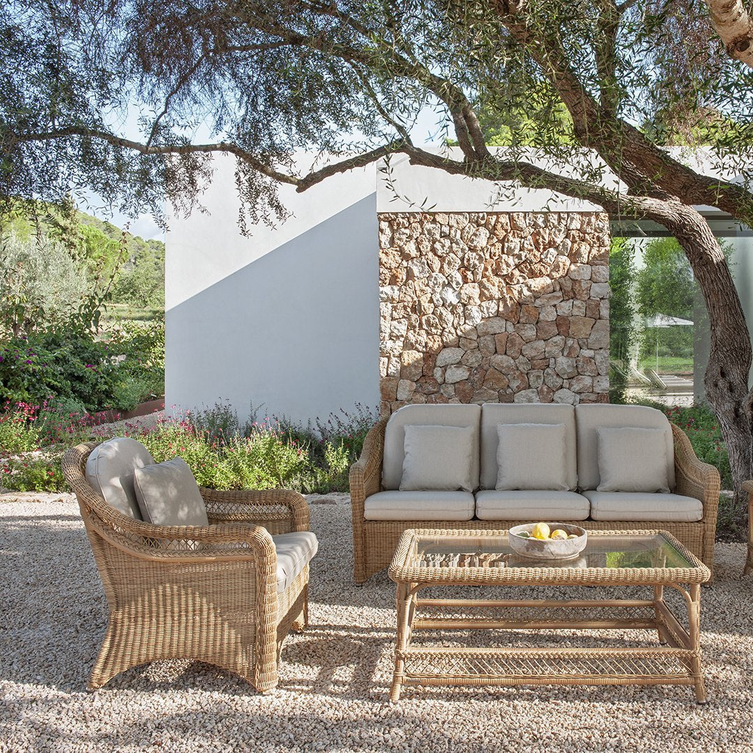 Beige cushioned seating and woven rattan in a serene outdoor setting with earthy tones and natural textures.