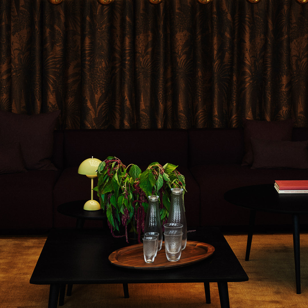 Dark brown patterned curtains with a rich texture, complemented by a black sofa and earthy wooden tones.