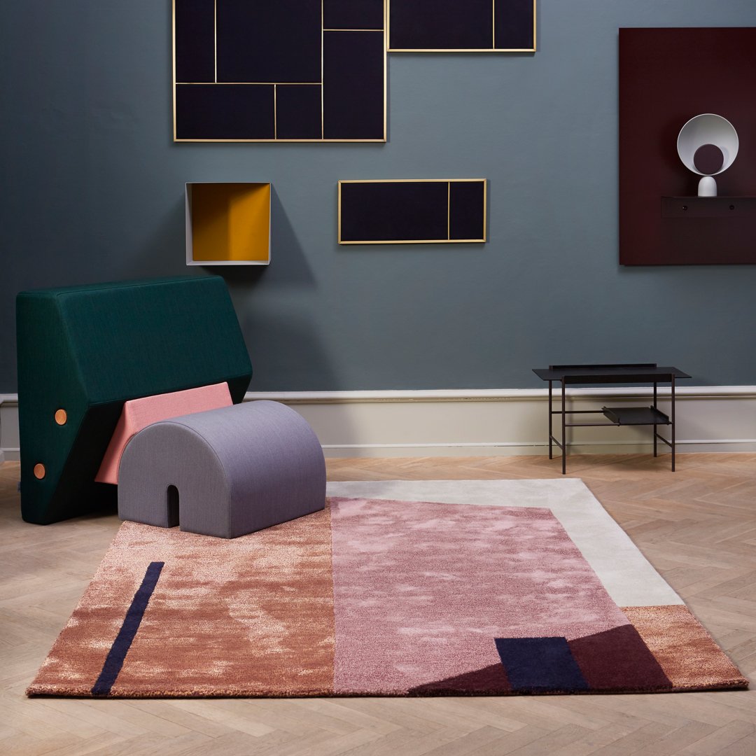 Colorful geometric rug featuring pink, purple, blue, and beige patterns, set in a modern interior. 