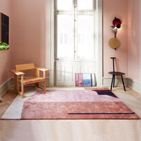 Abstract geometric rug featuring soft pink, white, and deep blue hues. Cozy home decor accent.