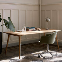 Light wood desk with natural finish, paired with a soft green chair on a textured gray patterned floor.
