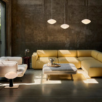 Modern living room featuring a yellow sectional sofa, white armchair, and minimalist decor against a concrete backdrop.