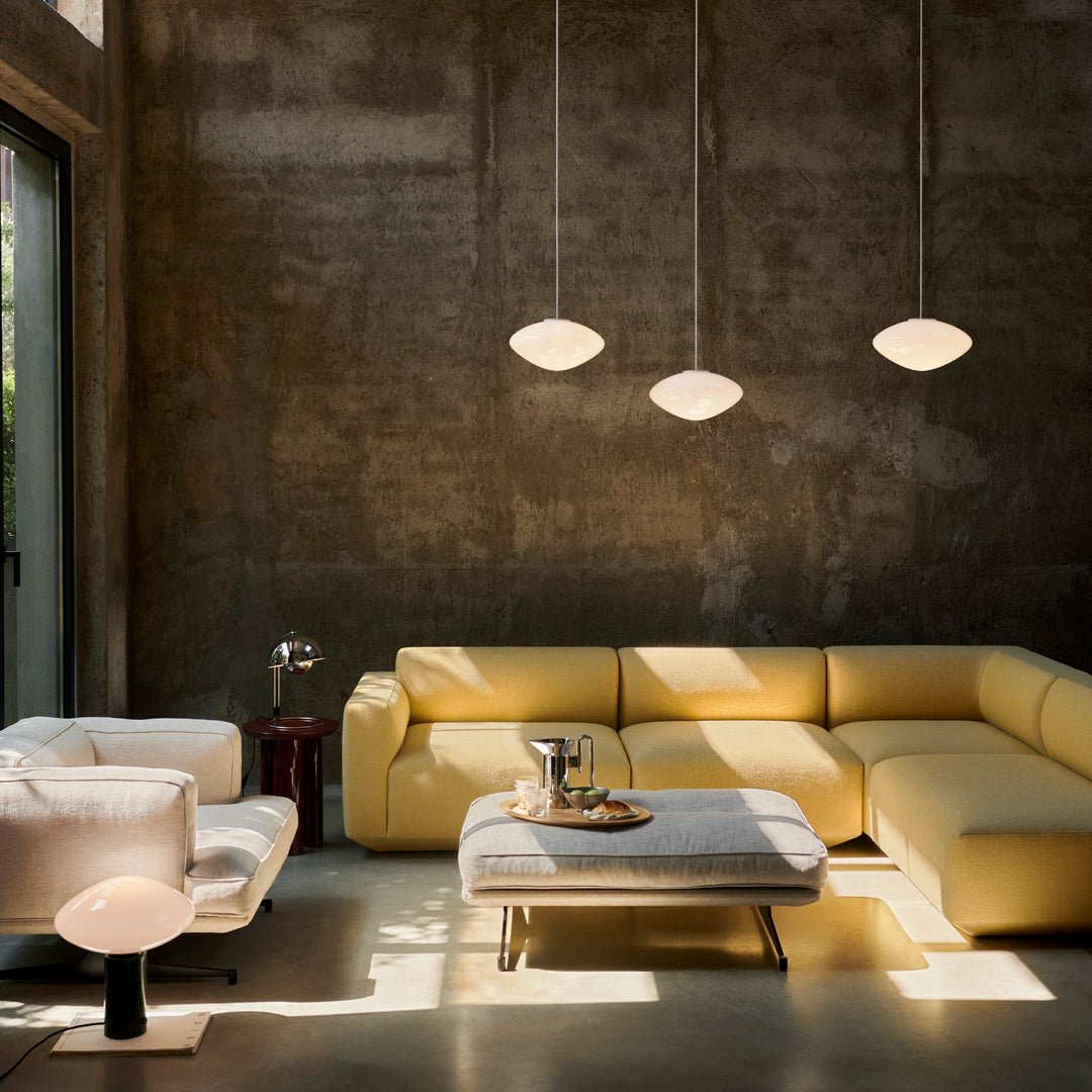 Modern living room featuring a yellow sectional sofa, minimalist white pendant lights, and a textured gray wall.