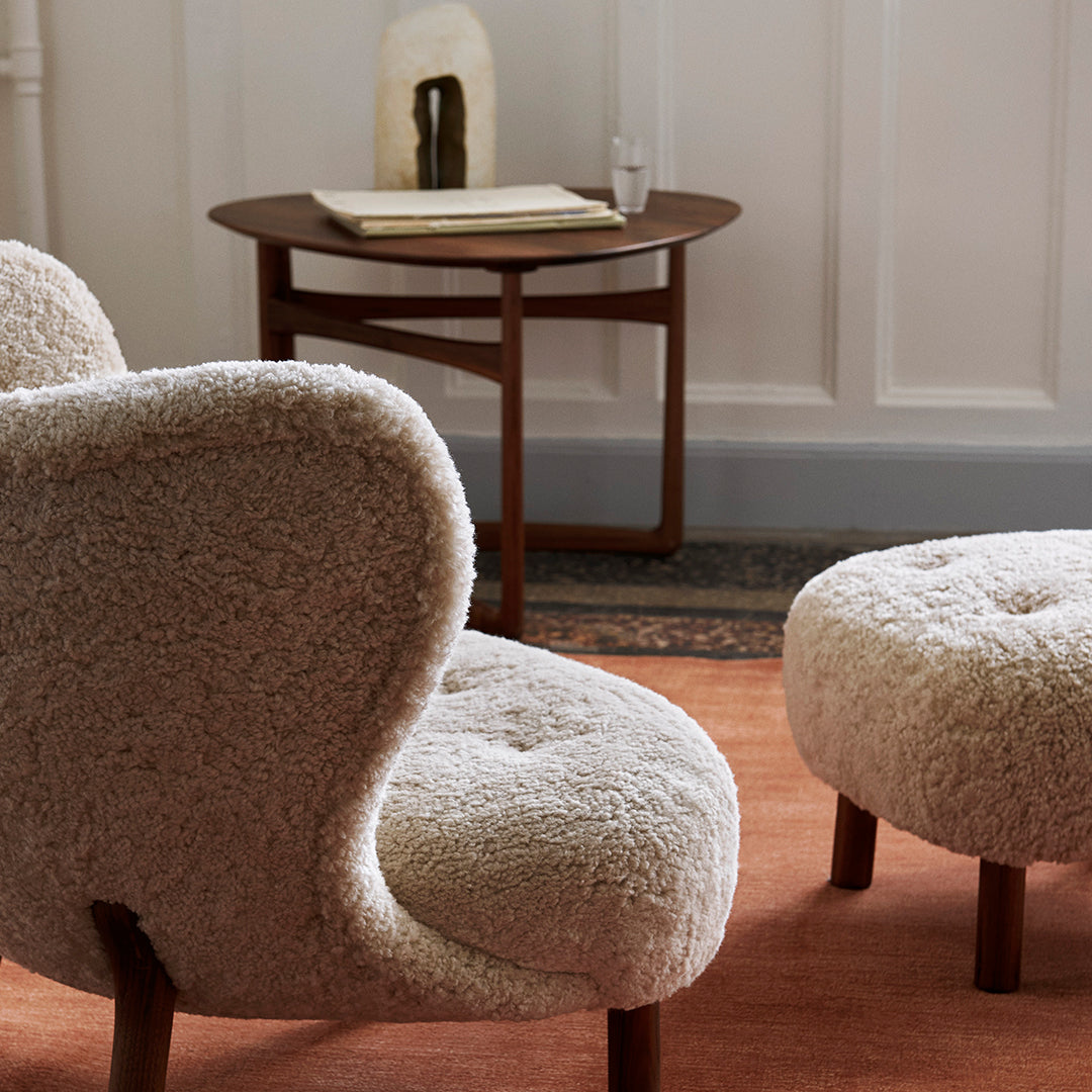 Beige textured chairs with a soft, fluffy pattern, paired with a round brown table on a warm-toned rug.