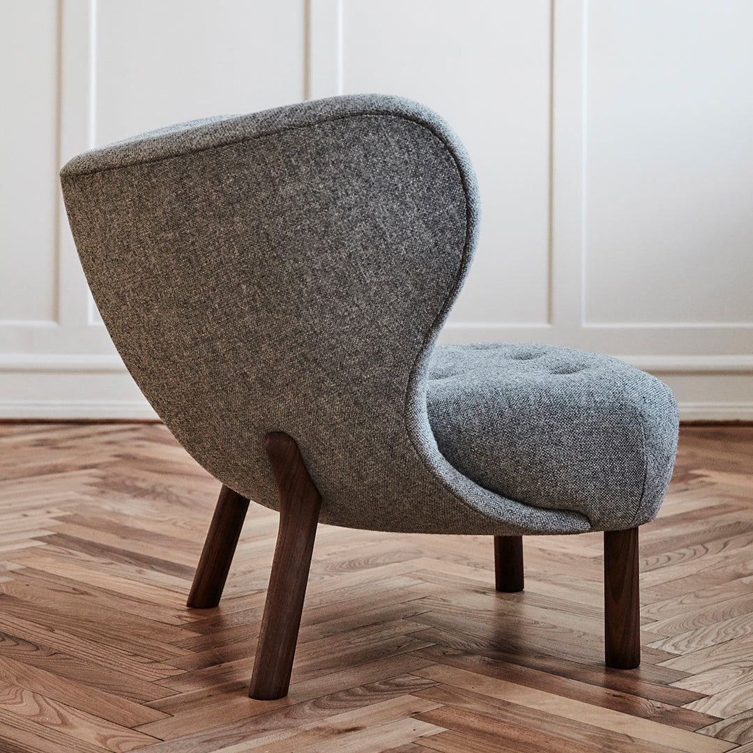 "Gray upholstered chair with a curved back and wooden legs, featuring a textured fabric on a hardwood floor."