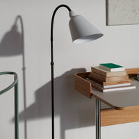 Stylish gray lamp with black stand, casting soft shadows against a minimalist background and arranged books.