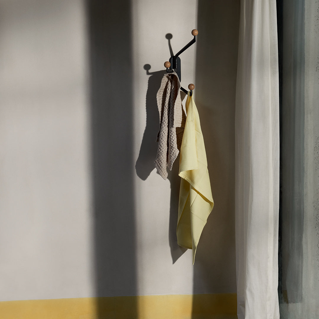 “Yellow and brown checkered towels hanging against a neutral wall with soft shadows for a warm, inviting feel.”